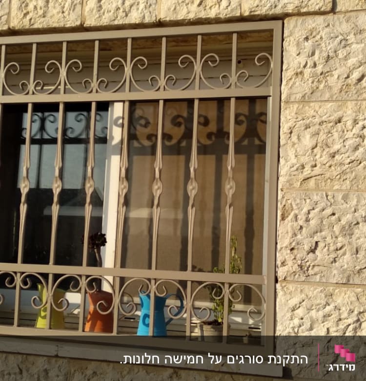 סורגי מתכת מעוצבים על חלון אבן